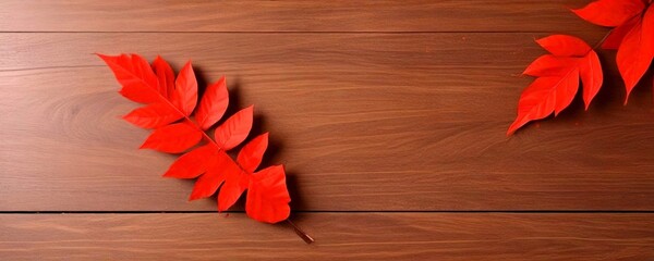 Poster - Two vibrant red leaves rest on a wooden surface, their glossy texture contrasting with the natural grain of the wood