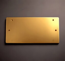 Fototapete - A rectangular, gold-colored metal plaque with two small holes on either side, mounted on a dark gray wall