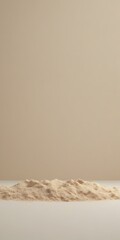 Leinwandbilder - A mound of light brown powder sits on a white surface against a beige background