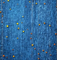 Poster - a close-up view dark blue denim fabric with numerous small orange buttons scattered across the surface