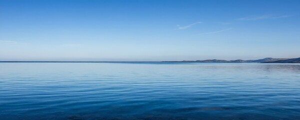 Poster - A serene calm body of water reflecting the clear blue sky, with distant mountains visible on the horizon