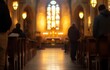 © kkkiim graphic - Blurred empty church background with soft focus on stained glass windows and altar, people in the foreground.