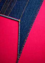 Aufkleber - a close-up view of a pair of jeans with a vibrant red background. The jeans have a blue denim upper and a pink denim lower, with the upper part featuring a diagonal line and