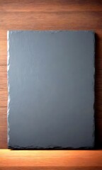 Poster - A dark gray slate rests on a wooden surface, its rough texture contrasting with the smoothness of the wood