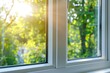 © Marina Demidiuk - New plastic PVC window with white metal frame installed at modern house, view of blurred green trees, blue sky. Advertising. Typical installation of insulated glazing windows with uPVC window frames.