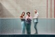 © Seventyfour - Full length shot with geometric composition of business people smiling at camera while standing on second floor of contemporary office building against concrete wall, copy space