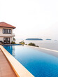 © JuanM - Luxury villa overlooking a serene infinity pool at sunset on a tranquil coastal resort