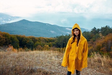 Vibrant yellow raincoatwearing woman enjoying nature in a mountain field under a clear sky on a travel adventure