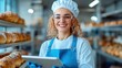 © Pinklife - A smiling young female baker stands confidently in a lively bread bakery, holding a digital tablet and surrounded by perfectly baked bread, filled with joy and purpose.