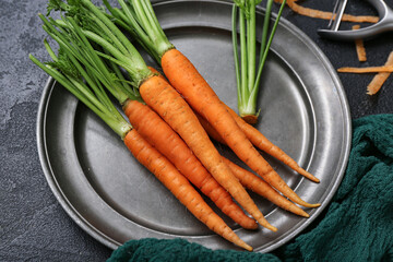 Plate of fresh carrots on black textured background