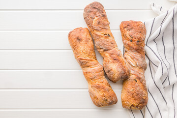 Canvas Print - Crusty rustic baguette on white table. Top view.