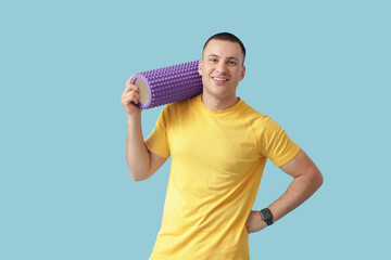 Sticker - Sporty young man with foam roller on blue background