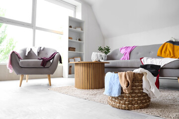 Canvas Print - Interior of living room with laundry basket and clothes on sofa