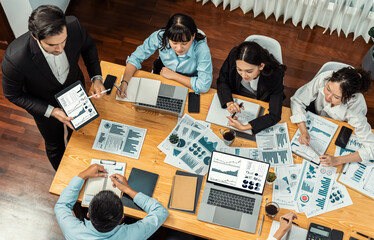 Wide top view of diverse group of business analyst team analyzing financial data report paper on meeting table. Chart and graph dashboard by business intelligence analysis. Meticulous