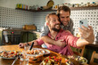 © Marko Geber - Gay couple enjoying lunch together at home and taking selfie