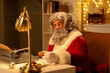 © Pixel-Shot - Santa Claus with typewriter eating cookies while writing Christmas story at night
