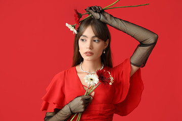 Poster - Beautiful young woman with gerbera flowers on red background