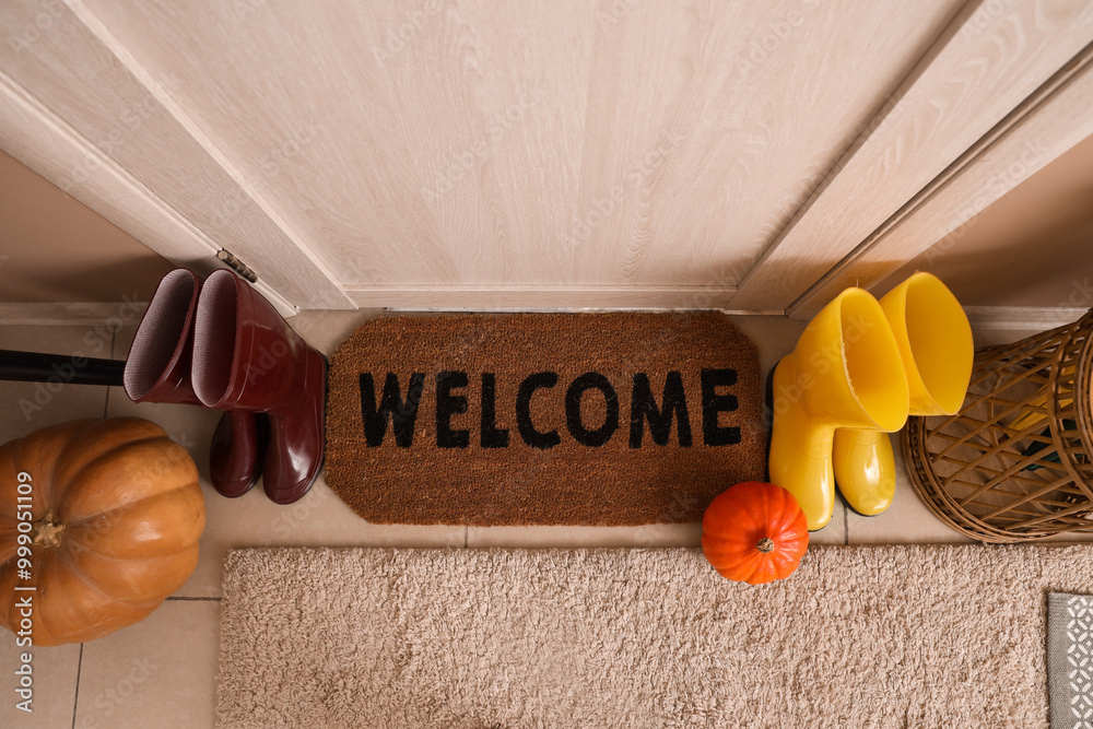 Door mat with shoes and pumpkin in hallway. Autumn interior concept