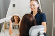 © Marko - A patient sits in a dental chair, holding a mirror to see their smile while a dentist stands beside her, both smiling. The setting is a modern dental clinic with bright lighting.