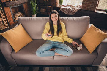 Canvas Print - Full body photo of charming teen girl sit sofa eat snacks watch tv hold remote controller wear yellow clothes modern interior flat indoors