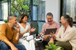 © Wavebreak Media - Using tablet, senior diverse friends laughing and discussing VR headsets in living room, at home