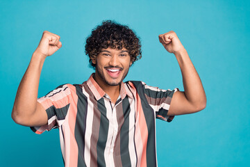 Wall Mural - Photo of nice young man raise fists wear shirt isolated on teal color background