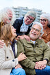 © CarlosBarquero - Vertical. Group of seniors grey hair joyful people having fun together sitting on bench in urban. Cheerful mature Caucasian friends meeting talking funny enjoying free time laughing autumn day outdoor