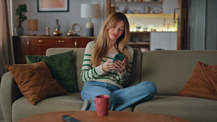 Woman chatting cellphone home couch. Relaxed lady making online order smartphone