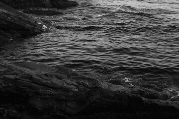 Stormy waves on a rocky seashore. Black and white sea