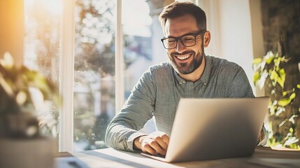 Canvas Print - Happy man working on laptop by the window