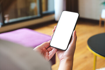 Wall Mural - Mockup image of a woman holding mobile phone with blank desktop white screen at home