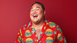 © Luluraschi - a happy Hawaiian man in hamburger-themed pajamas, showcasing laughter against a vibrant red backdrop