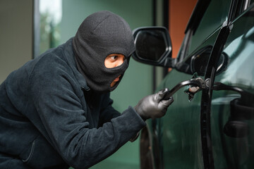 Wall Mural - Thief in uniform black jacket various action stolen cars. The Robber terrorism criminal car with balaclava and crowbar breaking into a car window