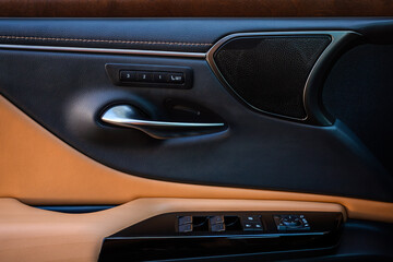 Interior of a modern car with leather inserts. Side door buttons: window lifters, mirror adjustment buttons, door lock. Inside the car.