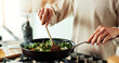 © HockleyM3/peopleimages.com - Spoon, cooking and hands of woman in kitchen with food, health and wellness with traditional recipe for lunch. Diet, nutrition and girl with frying pan, vegetables and meal prep for dinner in home.