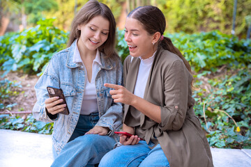  two happy teenage friends using smartphone app outdoors.