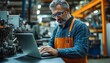 © Thanaseth - Engineer with glasses, middleaged, using laptop in factory, looking around at equipment, producing modern electronic components for industries