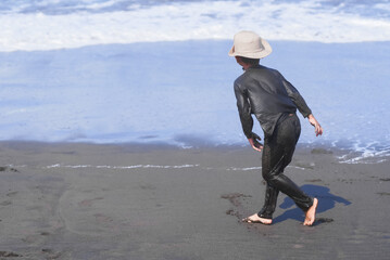 a boy wearing a hat playing on the beach