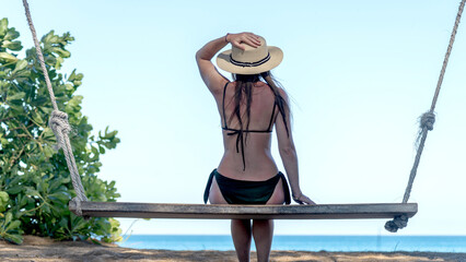 Girl on a swing on the beach by the sea