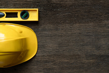 Wall Mural - Yellow building level and helmets on the old wood table, engineering eqipment tool concept