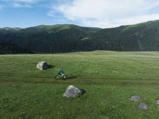 Wall Mural - Woman riding mountain bike on beautiful flowering grassland mountain top