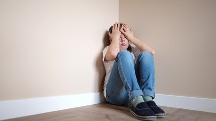 sad girl sitting in the corner crying a covered her face indoor with her hands. family violence abuse child concept. parents punished the child put in a corner. child in depression crying lifestyle