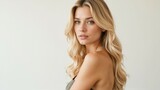 Portrait of a beautiful young blonde woman with flowing hair posing against a light background