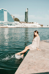 Wall Mural - A woman is sitting in the water wearing a white dress. The water is calm and blue. The woman is enjoying the moment and taking in the beauty of the scene.