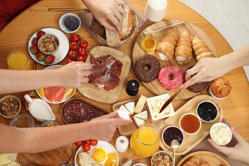 Sticker - Women eating different food during brunch at wooden table, top view