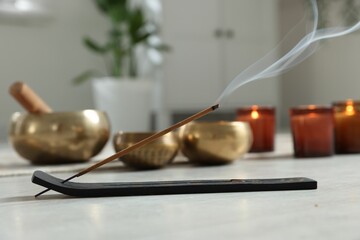 Incense stick smoldering in holder on white table