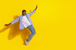 © deagreez - Photo of young model guy wearing casual checkered shirt and jeans standing tiptoes flexing isolated on yellow color background