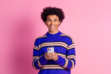 Poster - Photo of smart clever man guy with wavy hair dressed knitwear sweater holding smartphone in hands isolated on pink color background