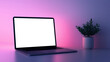© NaphakStudio - A modern laptop sits on sleek surface, illuminated by soft purple and pink lighting, alongside small potted plant, creating serene workspace atmosphere.
