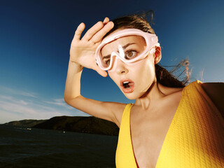 Poster - Title surprised woman in yellow swimsuit holding goggles description woman in yellow swimsuit holding goggles up to her face, looking at the camera with a surprised expression, capturing the essence